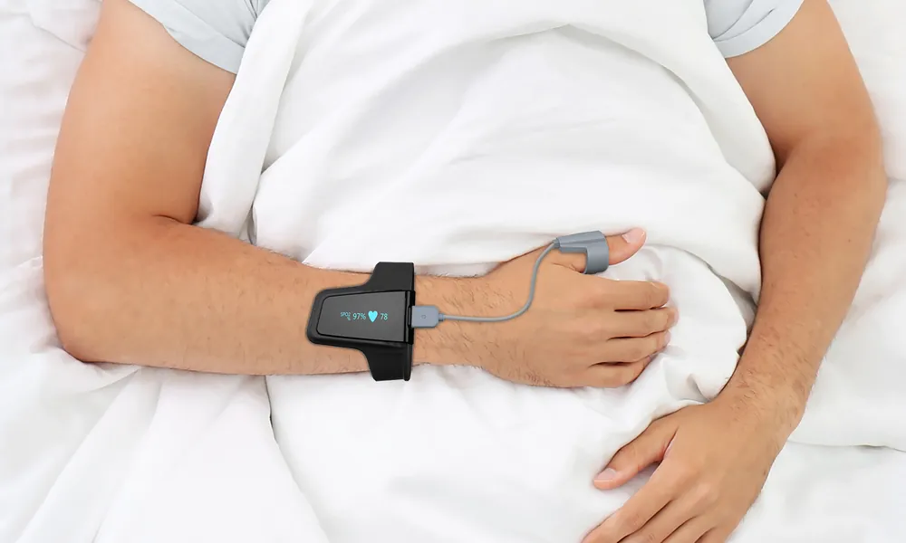 A person asleep in bed wearing the Sliiip home sleep test sensor on the wrist, with a small probe on one finger